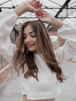 Brown haired girl in white linen summer shirt with hands raised up