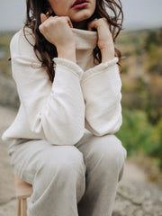 Girl sitting in sustainable fashion organic cotton turtle neck sweater and linen pants